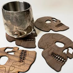 three wooden masks and a metal cup on a table