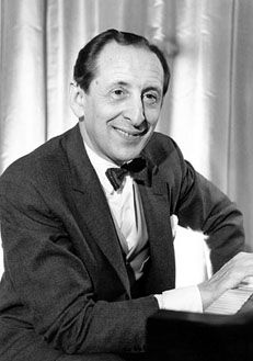 a man in a tuxedo sitting at a piano