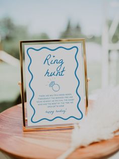 a sign that is on top of a wooden table next to a white and blue feather