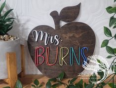 a wooden sign that says,'mrs burns'on it next to some potted plants