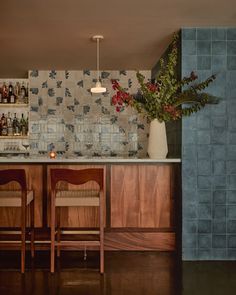 a kitchen with wooden cabinets and bar stools next to a vase filled with flowers