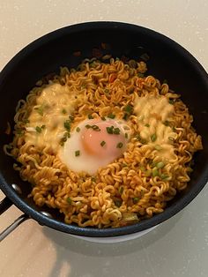 noodles and an egg are being cooked in a skillet