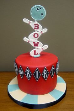 a red cake with bowling pins on top and the word bowling spelled out in white