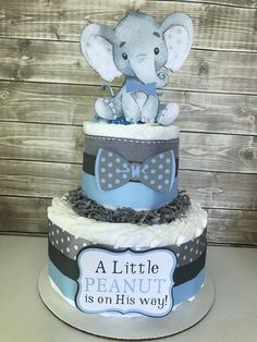 a blue and gray baby shower cake with an elephant on top