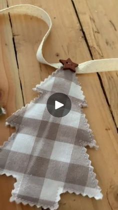 a christmas tree ornament made out of fabric on a wooden table with ribbon