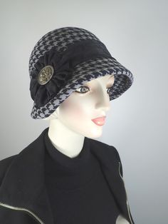 "Phinetta" is a one of a kind vintage-inspired cloche that's made completely by hand and is blocked over a vintage hat block. The steaming and blocking process produces it's unique shape. Once the hat is blocked, a wire is sewn into the brim to help it stay in the desired shape. I do all of the stitching by hand.  She is an interesting black and gray printed wool with a hounds tooth pattern.You won't see yourself coming and going in this special hat! It's simply embellished with a tone-on-tone black paisley silk band and rosette, topped with a large floral vintage metal button.  An asymmetrical brim is a flattering look on most women. This one comes to a soft point on the right side. As with traditional cloche hats, the back of the brim is short and shallow. A shallow back brim prevents th Stitching By Hand, Flapper Cloche, Tooth Pattern, Pretty Hats, Flapper Hat, Hat Blocks, 1920s Style, Hounds Tooth, Womens Winter