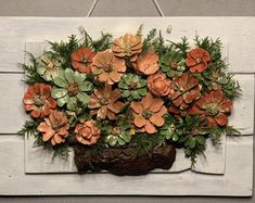 an arrangement of succulents in a pot hanging on a white board with wood planks