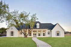 a large white house with a tree in the front yard and walkway leading to it