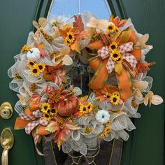 a wreath with sunflowers and pumpkins is hanging on the front door