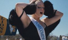 a woman wearing a black and white sash holding her hands behind her head