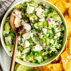 a white bowl filled with salad next to tortilla chips and lime wedges