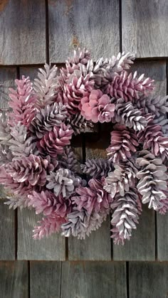 a wreath is hanging on the side of a wooden wall with pink and purple flowers