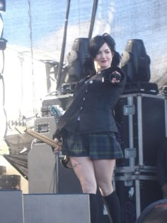 a woman in a kilt standing on stage with her arms out to the side