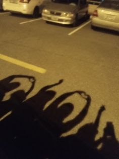 the shadow of a person riding a skateboard in a parking lot next to parked cars