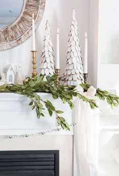 a fireplace mantel decorated with candles and greenery