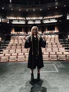 a woman standing in front of an empty auditorium with her hands up to the side