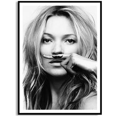 a black and white photo of a woman with a fake mustache on her face, in front of a brick wall