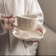 a woman holding a cup and saucer in her hands