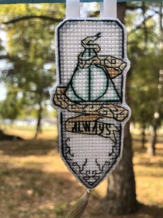 a cross stitch banner hanging from a clothes line in front of some trees and grass