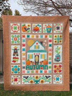 a quilted wall hanging on the side of a house with pumpkins and flowers