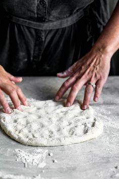 someone making homemade pizza dough with their hands on the top and one hand reaching for it