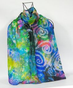 A silk habotai scarf hand painted in Ireland by Louise In summer shades of lilac, pink, blue, yellow and aqua with a design painted in the art of batik inspired by the Celtic spirals found on  the stone carvings found at Newgrange. Size 45 x 180 cm a light weight scarf that is very easy to wear Free shipping ships in Ireland in 1-2 days and up to 14 days for the rest of the world  I can ship directly as a gift and add a hand painted card with your message just let me know when you buy the scarf Blue Bohemian Hand-dyed Silk Scarf, Blue Bohemian Hand Dyed Silk Scarf, Artistic Hand Dyed Blue Silk Scarf, Artsy Multicolor Silk Scarf For Artistic Expression, Multicolor Bohemian Scarves With Batik Print, Bohemian Multicolor Scarves With Batik Print, Bohemian Hand-dyed Multicolor Silk Scarf, Handmade Bohemian Multicolor Silk Scarf, Handmade Multicolor Bohemian Silk Scarf