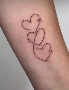 a small tattoo with two hearts and the letter m on it's side arm