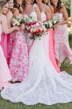 a group of women standing next to each other wearing dresses and holding bouquets in their hands