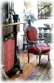 a red chair sitting in front of a fireplace next to a table with vases on it