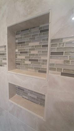 a white tiled bathroom with shelves and tile backsplashes in the shower area