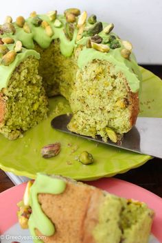 a cake with green frosting and pistachio toppings on a pink plate