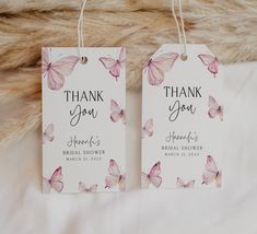 two tags that say thank you and have pink butterflies on them, sitting on a furnishing