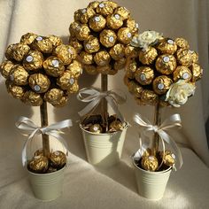 four vases filled with gold and white chocolate covered candies, tied in bows