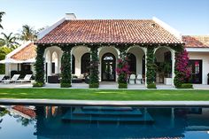 a house with a pool in front of it and flowers growing on the wall next to it