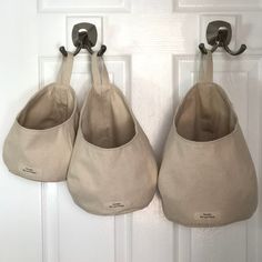 three purses hanging from hooks on a door