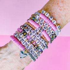 a woman's arm with several bracelets that have words on them and charms