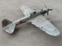 an old model airplane sitting on top of a cement floor next to a red star