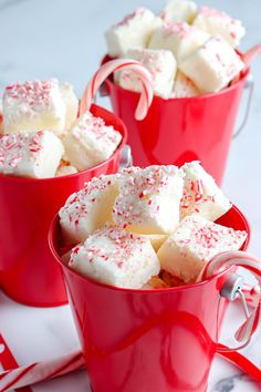 three red mugs filled with marshmallows and candy canes