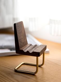 a small wooden chair sitting on top of a wooden table next to a laptop computer