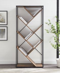 a book shelf with books on it next to a potted plant and framed pictures