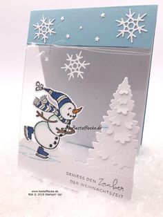 a christmas card with a snowman and trees on the front, in blue and white