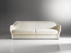 a white couch sitting on top of a floor next to a gray wall in an empty room