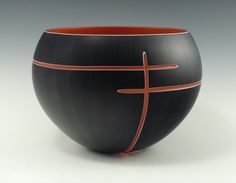 a black and red bowl with a cross painted on the side, sitting in front of a gray background