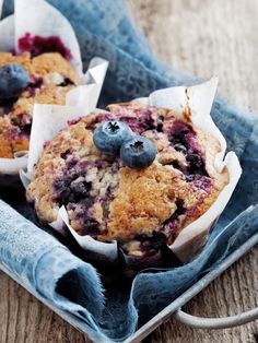 three muffins with blueberries and crumbs in them on a towel