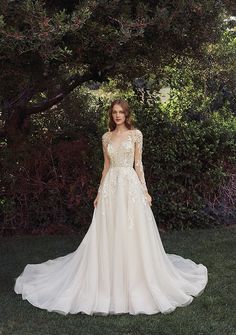 a woman wearing a wedding dress standing in the grass