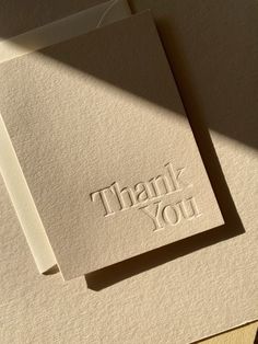 two folded thank cards with the words thank you on them, sitting next to each other