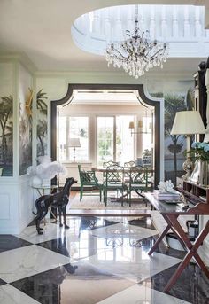 a living room filled with furniture and a chandelier hanging from the ceiling over a checkered floor