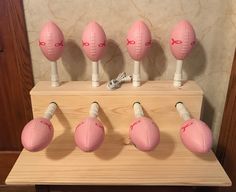 five pink footballs are lined up on a wooden shelf with white wires attached to them