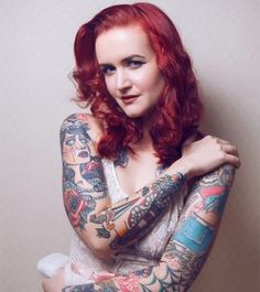 a woman with red hair and tattoos on her arms