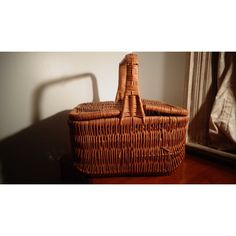 a brown wicker basket sitting on top of a wooden table next to a mirror